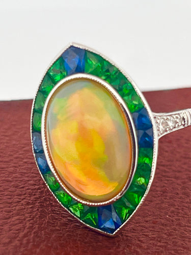 18k WG Opal cabochon ring with emerald and sapphire (5.18 ct) halo and diamonds